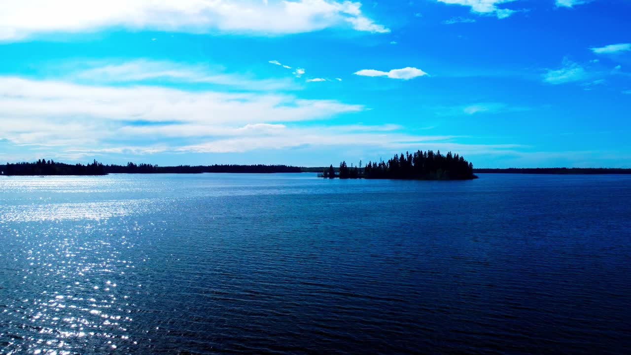 loon 새 서식지 호수 위로 평행한 여름 공중은 태양이 그라데이션을 설정할 때 반짝이는 물이 있는 삼림 공원으로 둘러싸인 중앙에 자연 섬이 있는 푸른 하늘 구름의 반사 보기