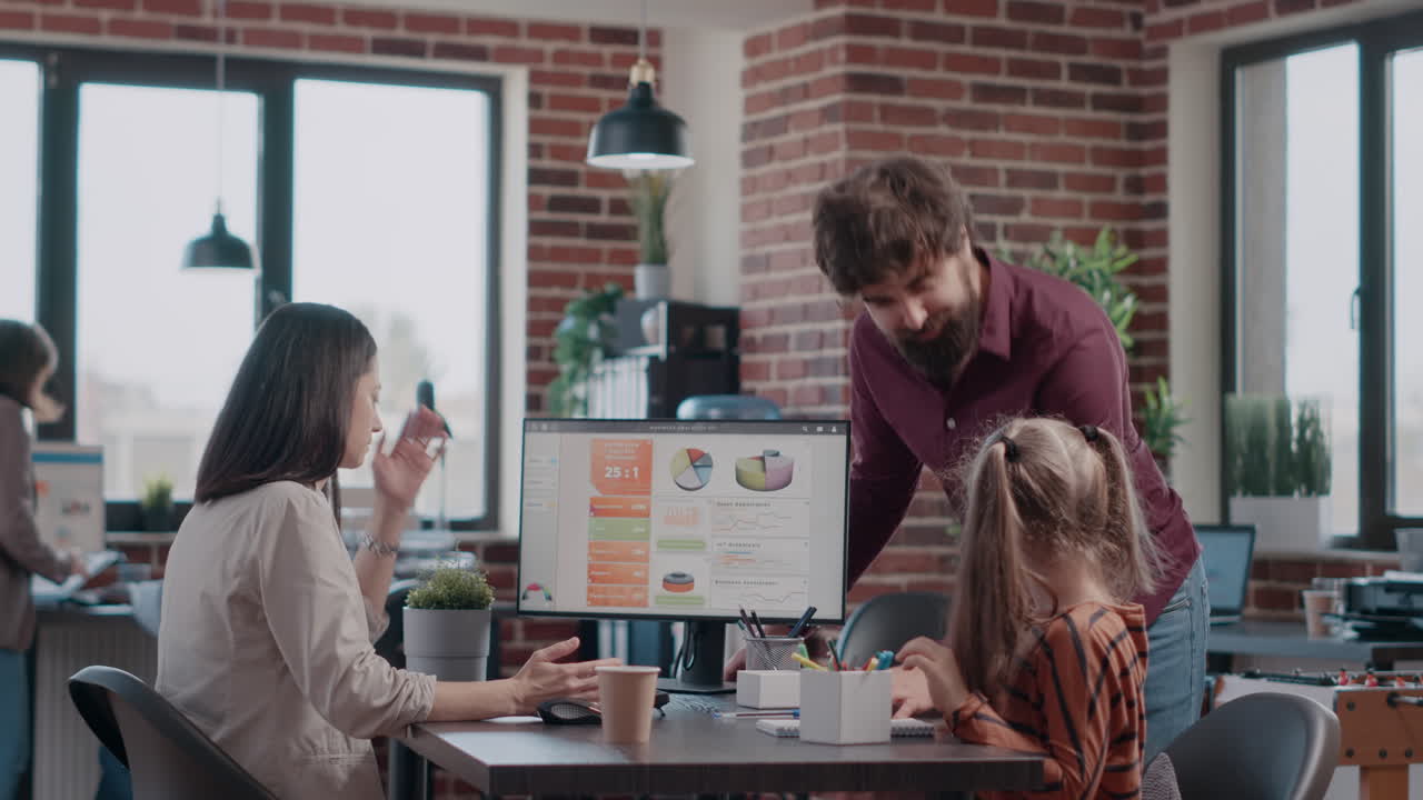 Working mother planning project on computer while colleague talking to child