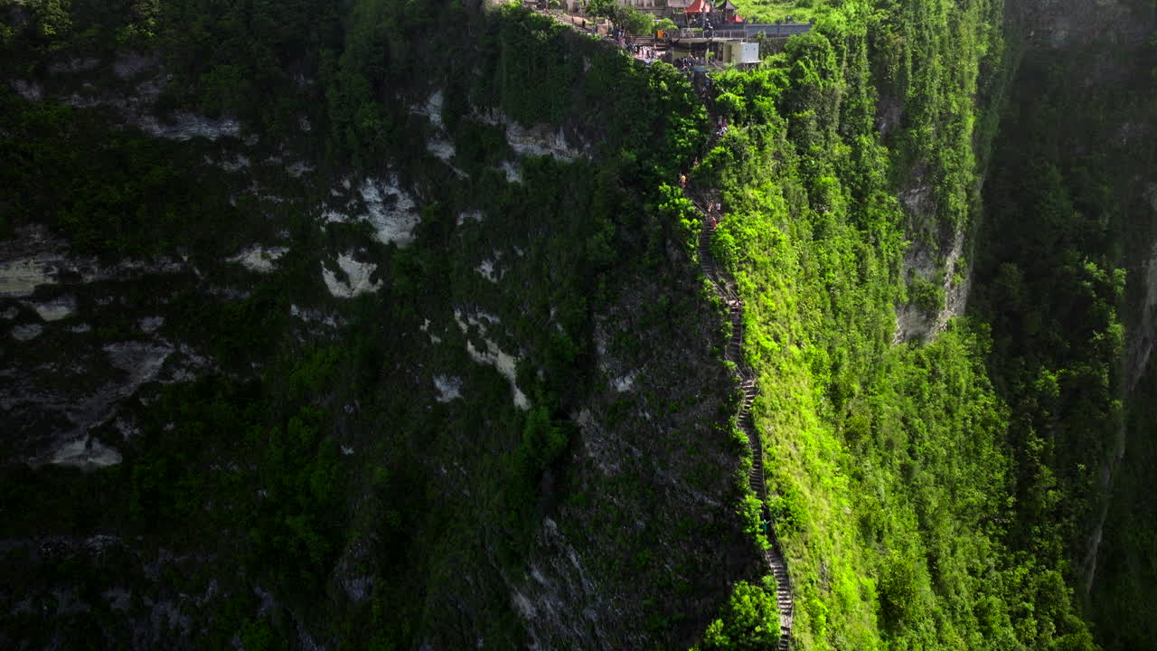 la inclinación aérea hacia abajo sigue escalones empinados en la cresta tropical a la playa de kelingking