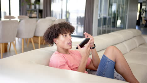 relaxing on couch, young man using smartphone and making video call at home