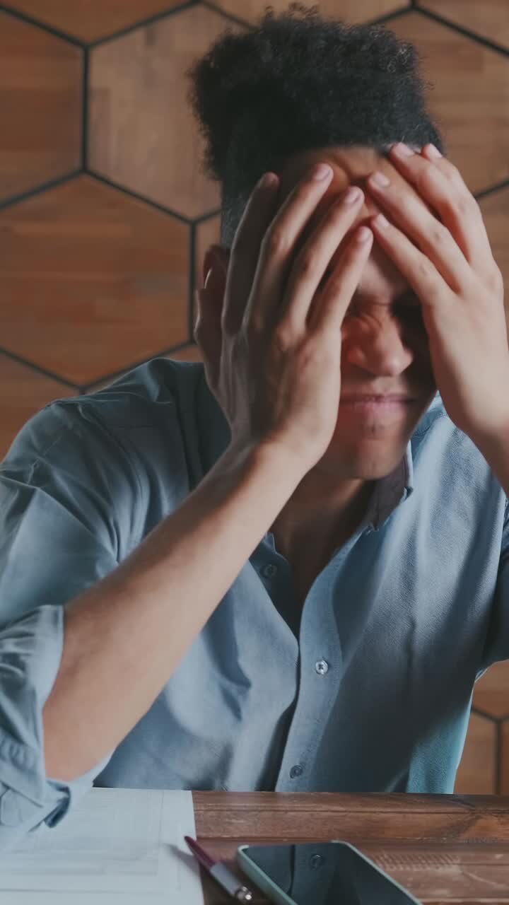 Young disappointed african american man gets upset and throws phone at desk