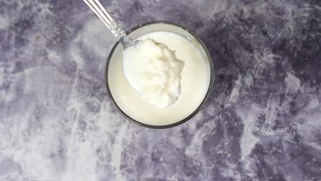 close-up of a glass of creamy yogurt with spoon