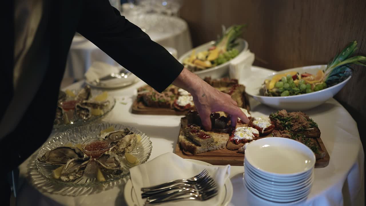 한 남자가 행사에서 뷔페에서 샌드위치를 집어 들고 있다.