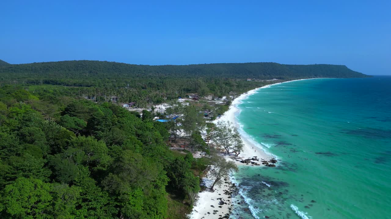 Black Stones in turquoise water gently washing the white sand beach of Koh Rong island, cambodia, on a sunny day with clear blue sky. Great aerial view flight drone shot footage from above