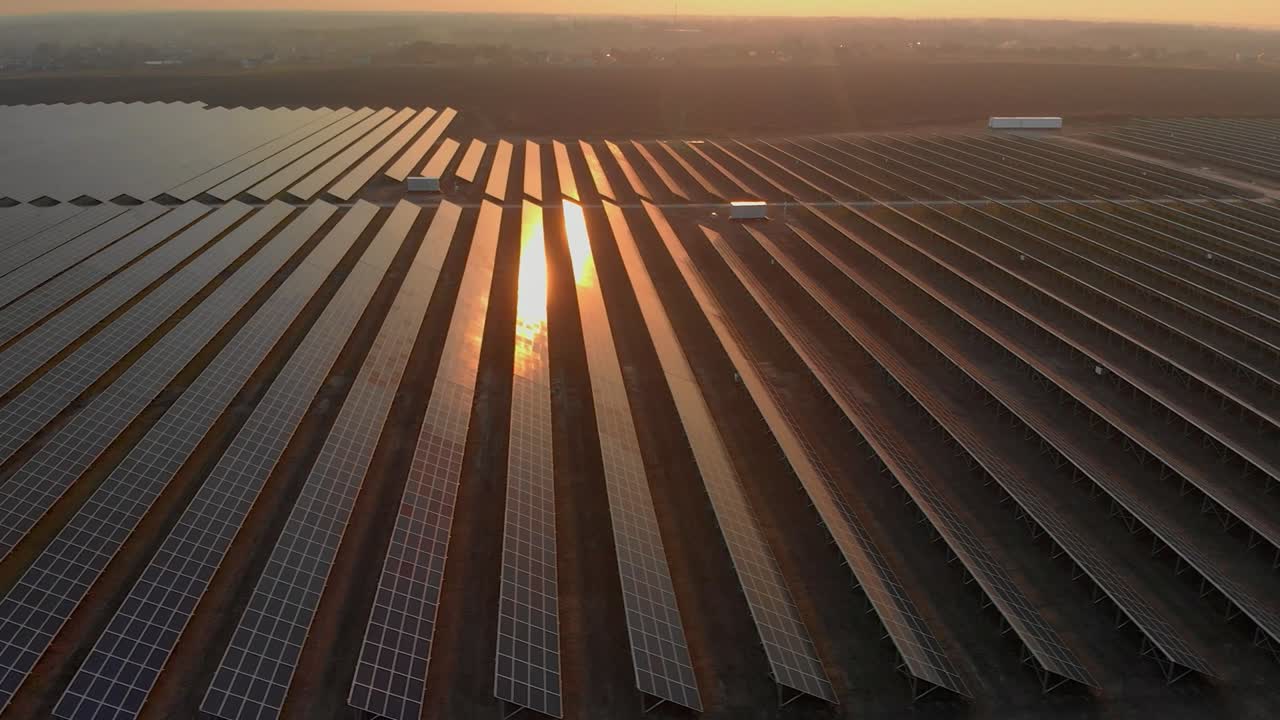 Aerial drone view into large solar panels at a solar farm at cloudy summer evening. Solar cell power plants, green grass. Footage video 4k.