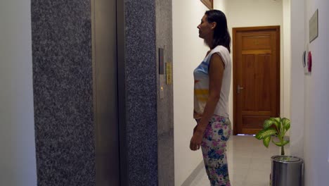The woman approaches the elevator, presses the button and enters the elevator