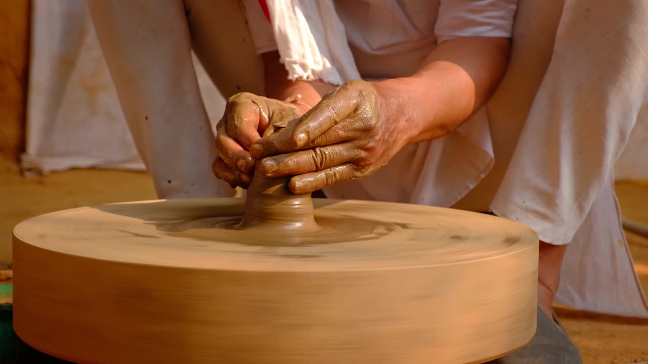 Mani esperte di un vasaio che modellano l'argilla sul tornio e scolpiscono un vaso. Shilpagram, Udaipur, Rajasthan, India