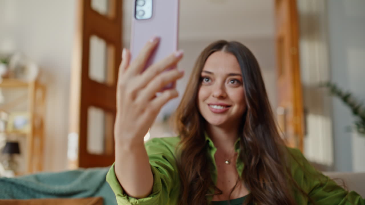 Primo piano di una donna che saluta durante una videochiamata tramite l'app per smartphone a casa. Ragazza entusiasta
