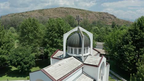 pedestal drone shot of st petka church's dome, and slowly orbitting around the rest of the buildings around the church, revealing the surrounding trees and mountains