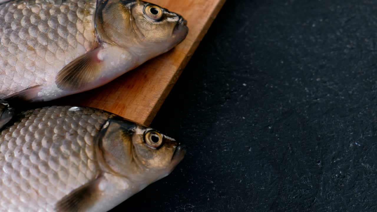 Tilberedning af fisk. Friske små karper på bordet på et træbræt, nærbillede.
