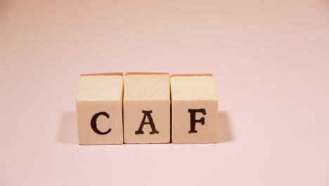 composing the word cafe with wooden letters on a pink background