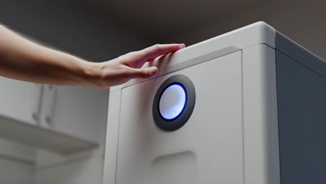 hand interacting with a smart device with a glowing blue button