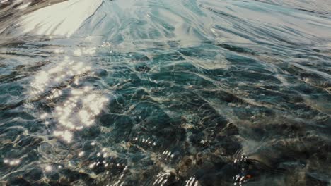 sun sparkles in stream of water running down the sand slope