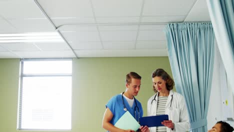 doctor and nurse standing by patient and discussing on medical report