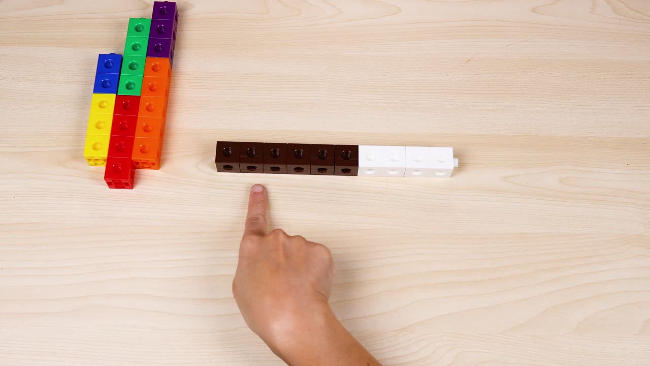 손은 테이블 위에 있는 다채로운 연결 큐브를 조작합니다.