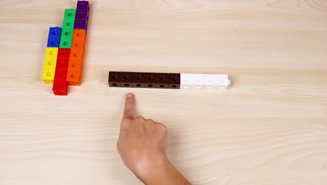 hands manipulate colorful linking cubes on table