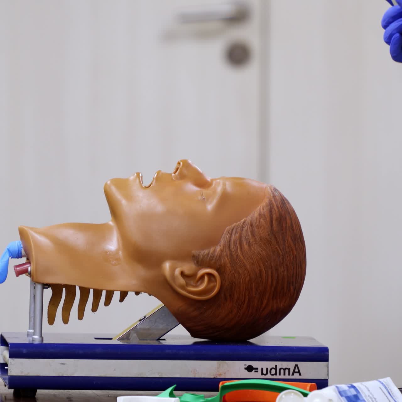 Testa di manichino utilizzata per l'addestramento alla tecnica di intubazione. Messa a fuoco selettiva sull'attrezzatura utilizzata dai tirocinanti nelle mani del medico.