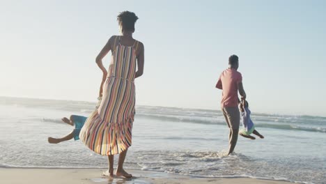 Glückliches-Afroamerikanisches-Paar,-Das-Mit-Tochter-Und-Sohn-Am-Sonnigen-Strand-Spielt