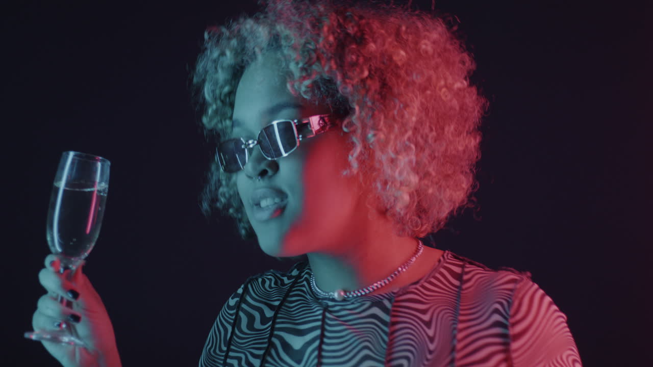 Stylish woman enjoying a champagne toast in neon light