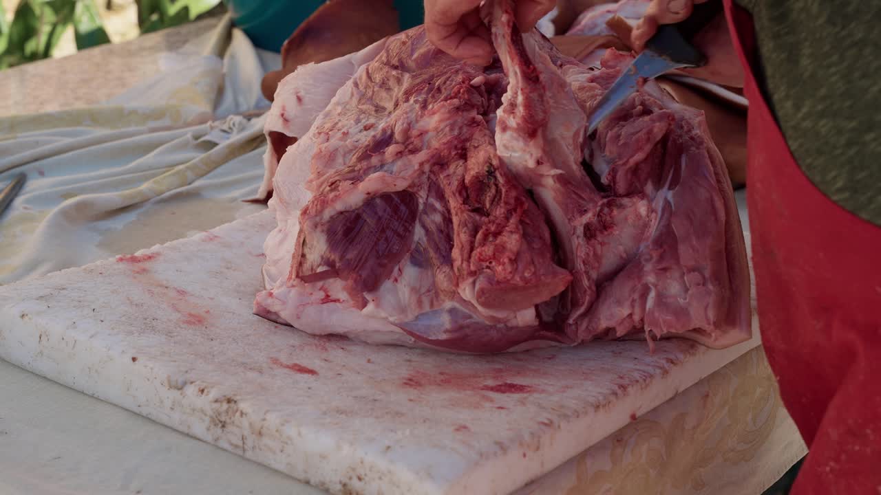 Cutting pork shoulder with knife during rural butchering in north Portugal Minho