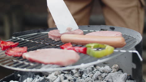 close-up of an unrecognizable man putting hamburger patties on grill