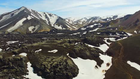 Hiking-trail-along-black-magma-rocks-and-white-snow-in-Landmannalaugar-mountains-in-Iceland