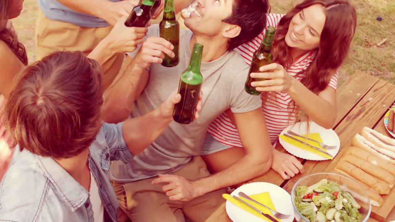 un grupo feliz de amigos animando en el parque con cervezas