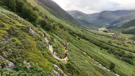 4k aerial angle of hikers ascending path to ben nevis mountain