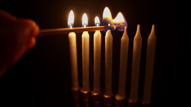 Hand Lighting Multiple Candles with a Matchstick in the Dark