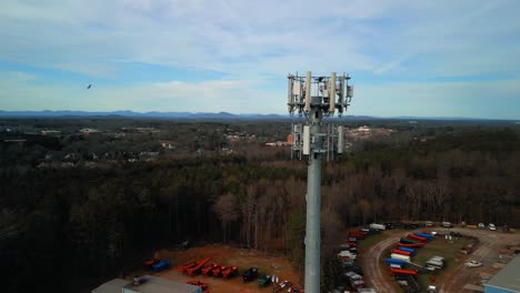 aerial shot revolving around cell phone tower surrounded by forest