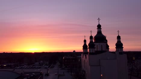 Langsame-Umlaufbahn-Kirche-Antenne-Stadt-Straße-Verkehr-Sonnenuntergang