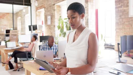 Portrait-of-happy-african-american-colleagues-with-tablet-in-creative-office-in-slow-motion