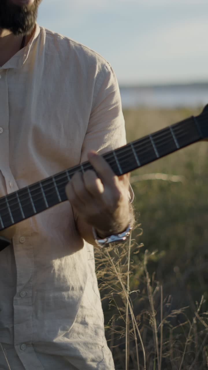 Homem tocando guitarra elétrica em um campo na hora dourada