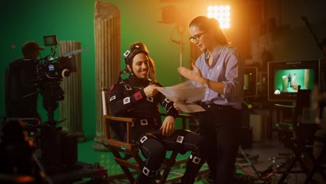 on film set: prominent female director explains scene to male actor wearing motion capture suit and playing green screen scene in superhero movie, they do high-five for successful box office results