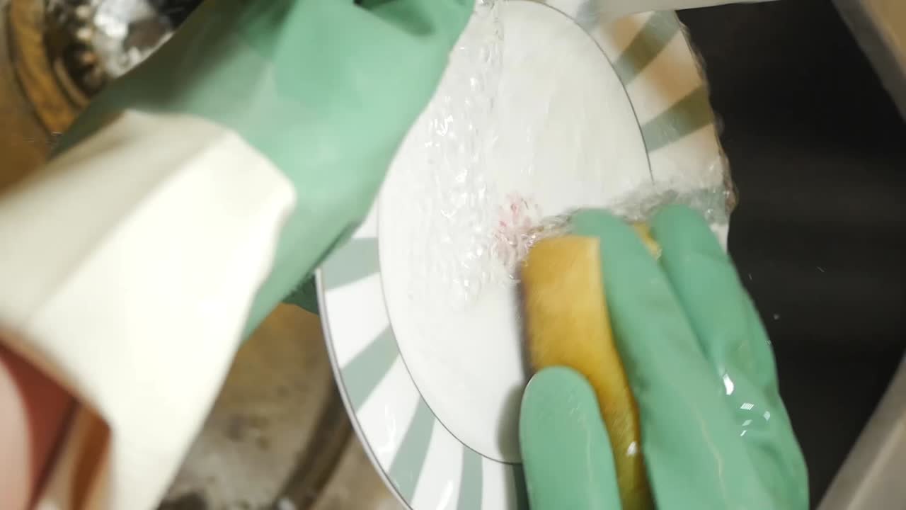 Washing dishes with gloves and a sponge