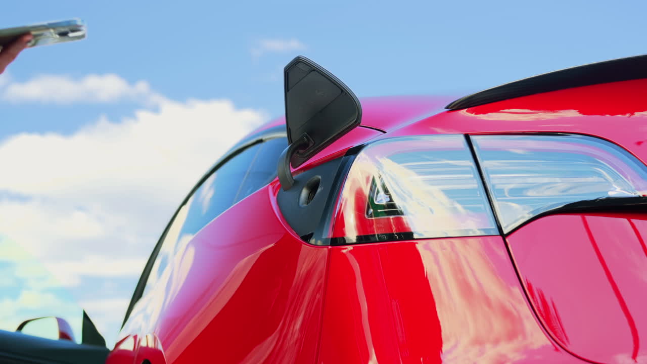 Close view of a woman tries to plug charger into her electric red car
