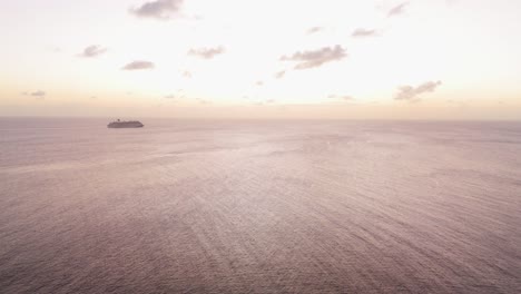 high angle aerial of golden hour sky light on ocean ripples with silhouette of cruise ship