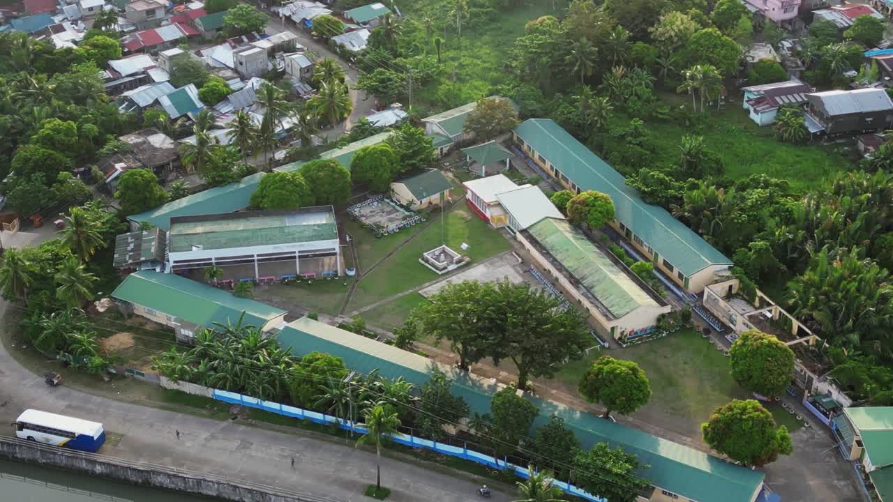 Orbiting aerial view of a scenic, rural elementary school in a quaint Philippine town with lush foliage. Virac, Catanduanes.