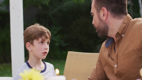 dad and son talking to each other while having lunch outdoors