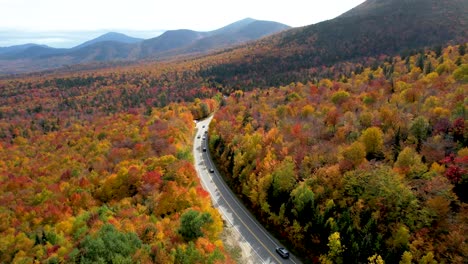 vista aérea de autos conduciendo a través del bosque en nueva inglaterra durante el otoño