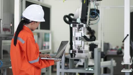 el oficial profesional comprueba el robot que se mueve en la base de la pieza en la fábrica de fabricación. reparación del brazo robótico en el laboratorio de investigación, uso de gafas de protección, uso de computadora compruebe el bucle del programa.