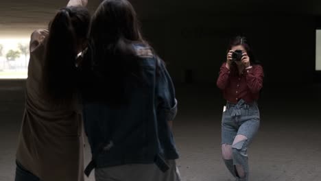 young asian woman photographer taking a photo with a professional camera to someone while posing