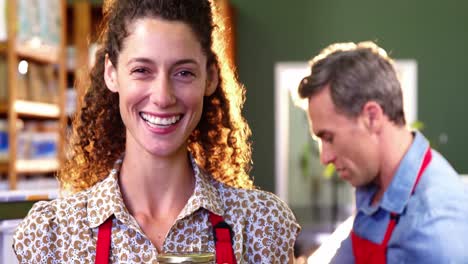 personal femenino sonriente sosteniendo un frasco en el supermercado