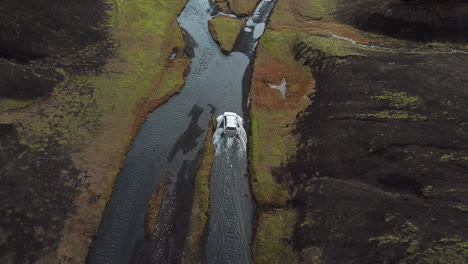 suv crossover vehicle in shallow river moving further on muddy road in amazing landscape of iceland