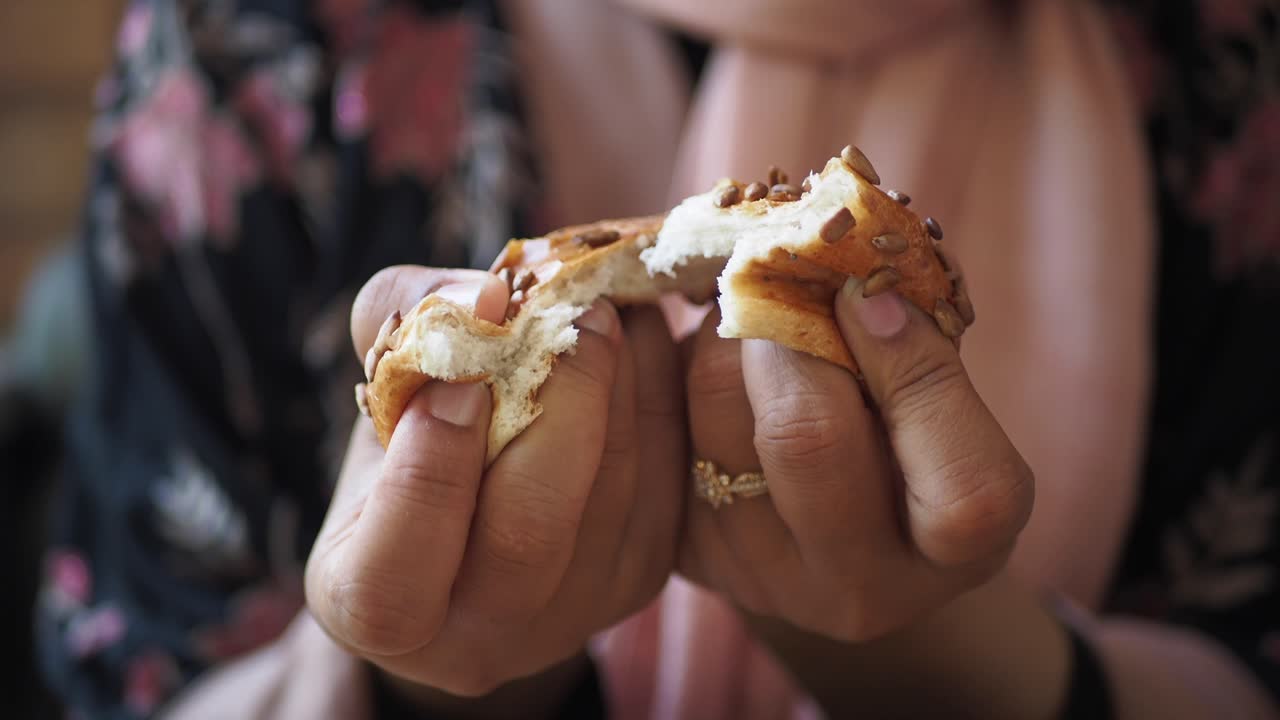 una mujer comiendo un pan de semillas.
