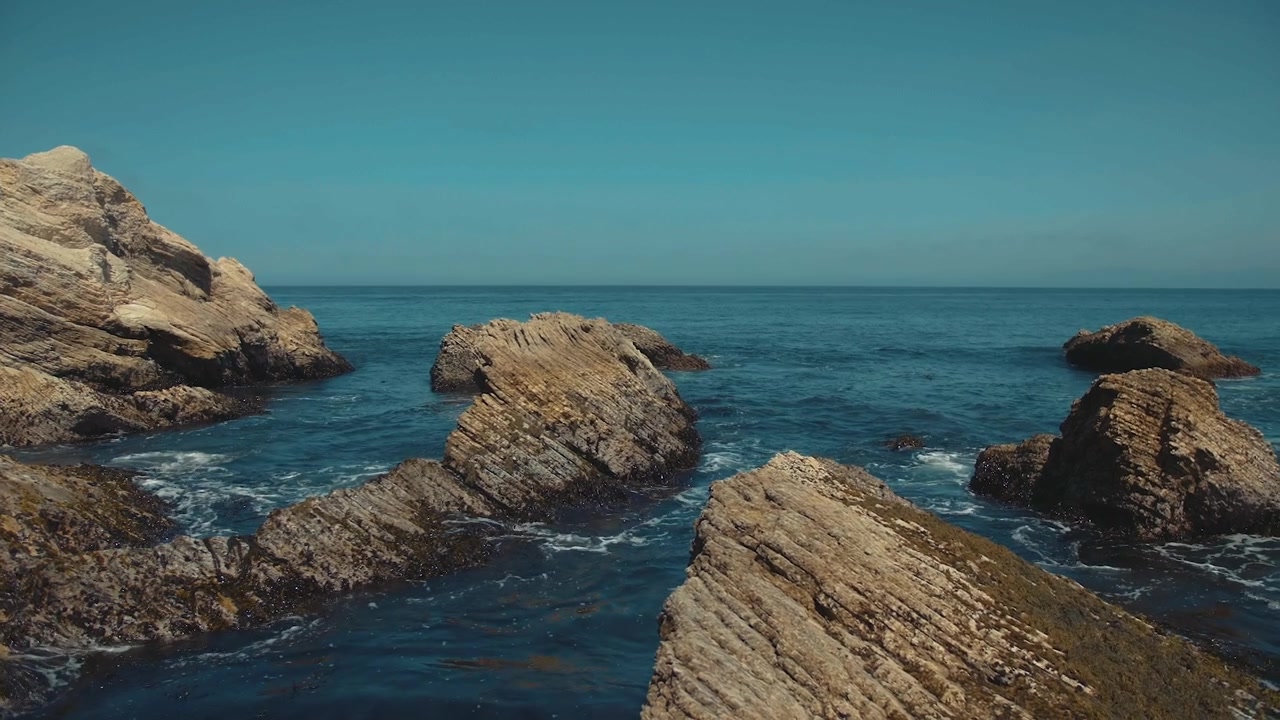 Tranquillo paesaggio marino con onde che lambiscono grandi formazioni rocciose