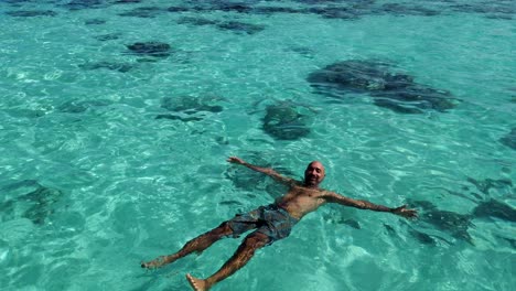 mixed-race man lying on his back floating and chilling in the crystal clear waters of moorea