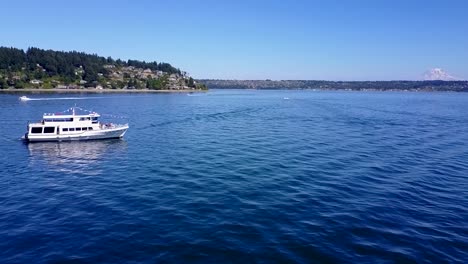 aerial, tracking, drone shot of a yacht leaving gig harbor, on a sunny day, in washington, usa