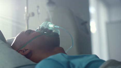 recovering patient with oxygen mask lying in bed emergency unit ward closeup.