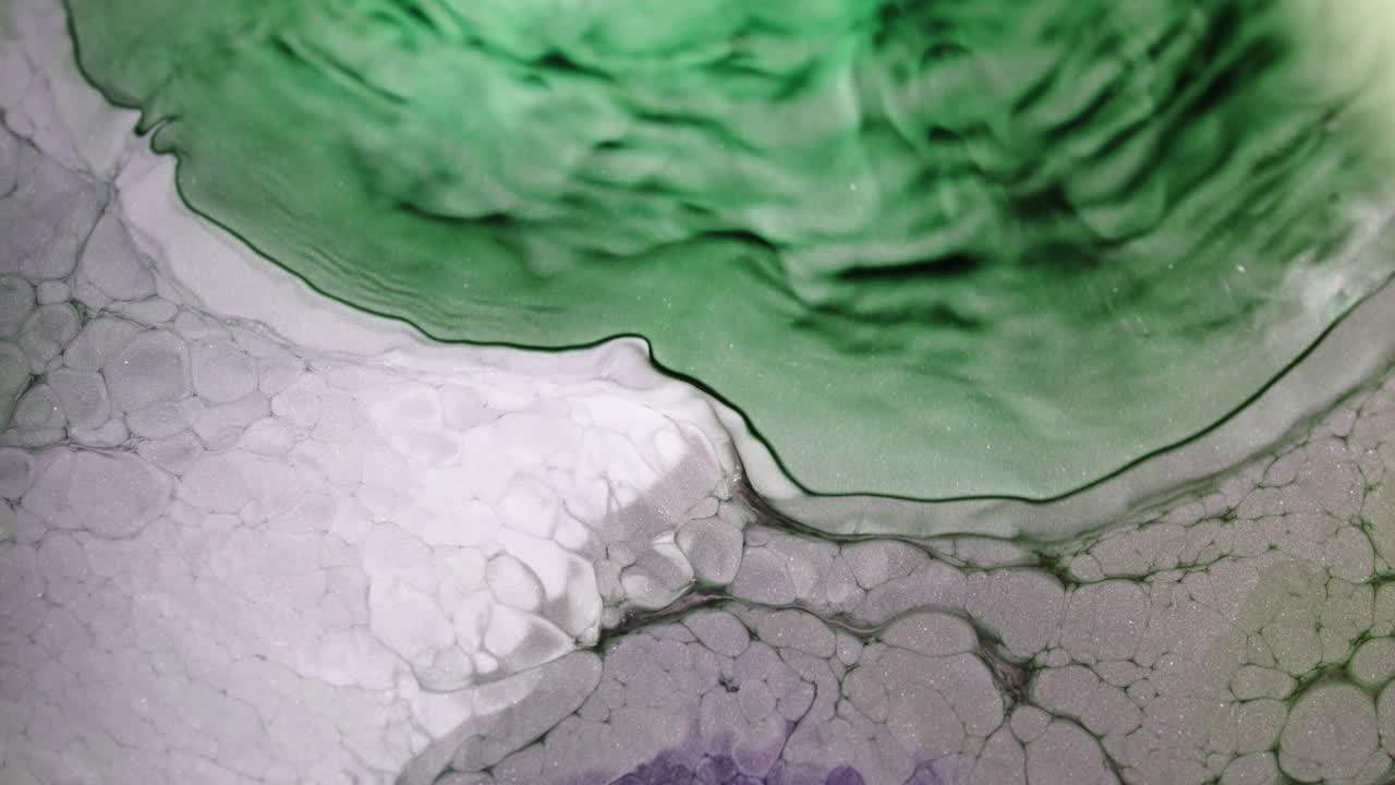 Colorful liquids blend in abstract organic patterns, close-up macro view, science art concept